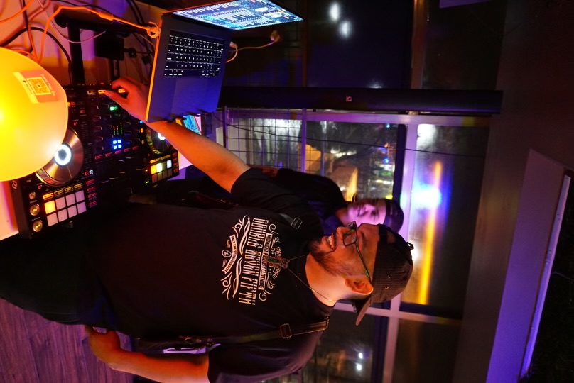 DJ smiling at the decks at Hookava during a Crawl Reno night event